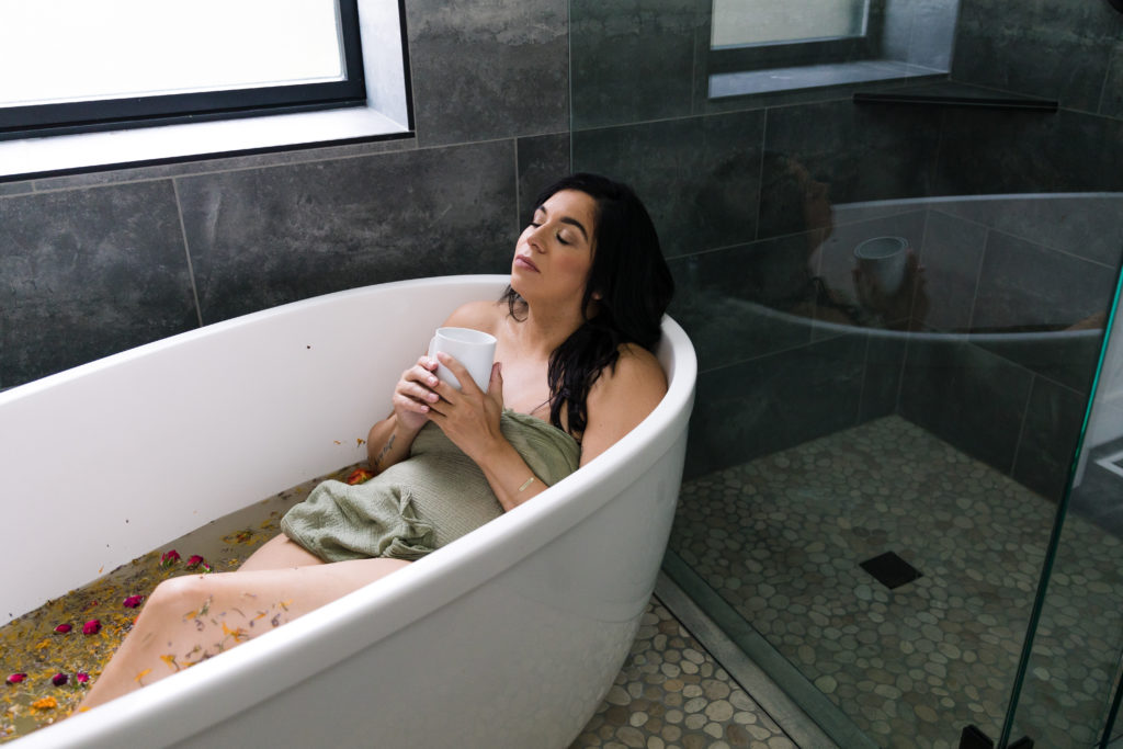 Woman relaxing with cup of tea in postpartum sitz bath