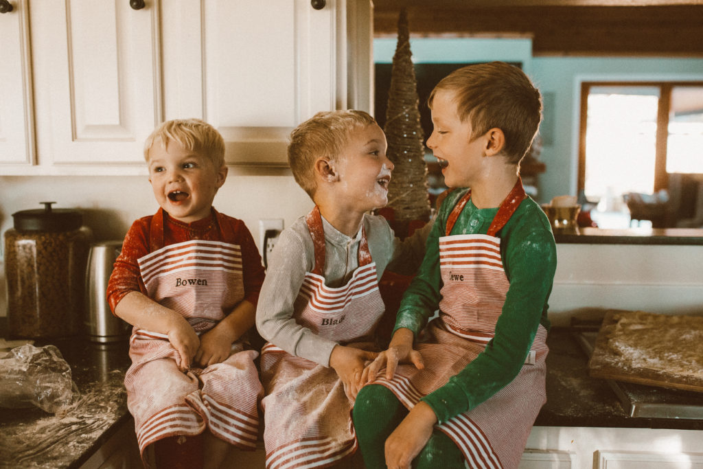 Three boys making cookies in the kitchen at Christmastime
