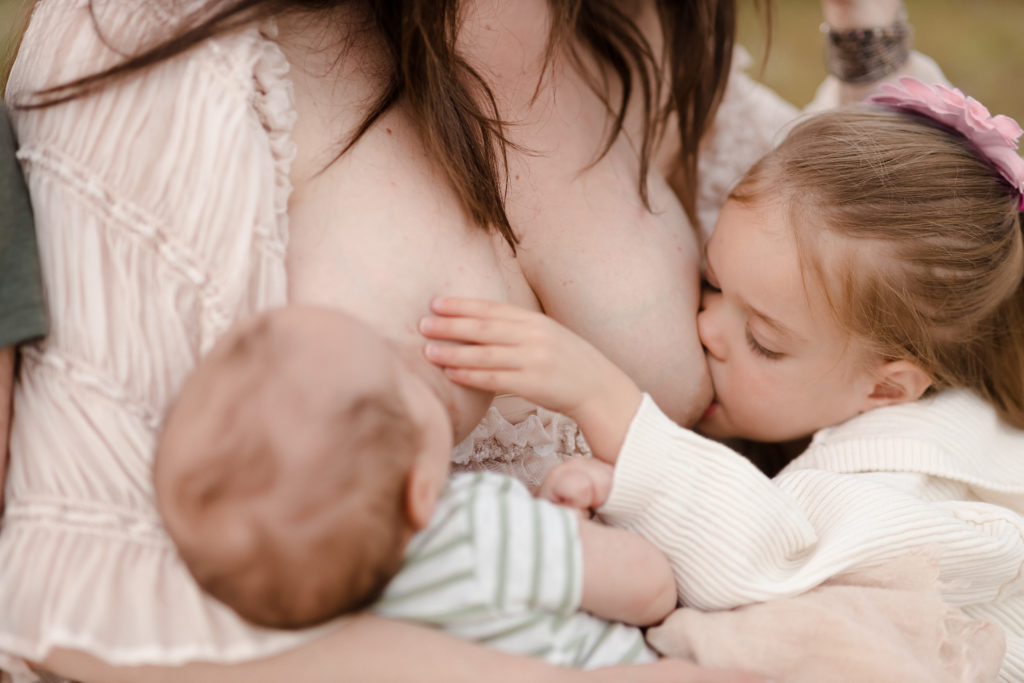 Mom breastfeeding children outdoors