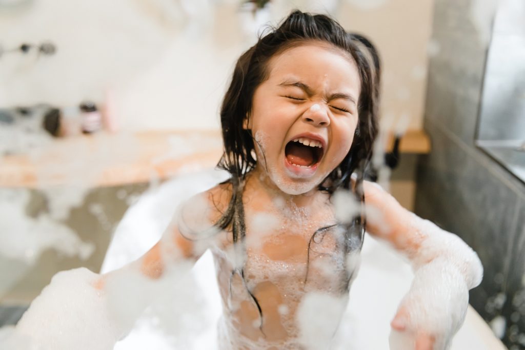 Little Asian girl playing in bubble bath during photo session at Glean & Co studio
