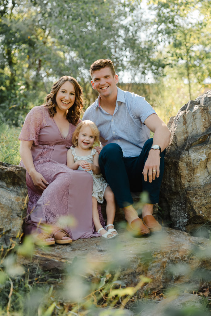 Family photos aren't just for fall, family seated on rocks in the woods in midsummer