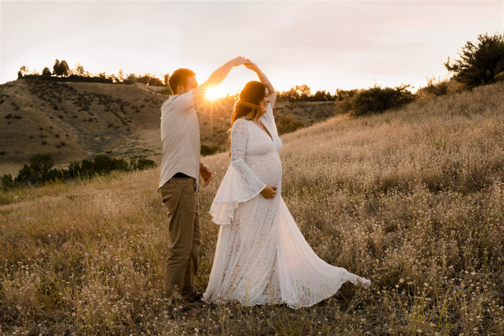 Couple dancing in a field at sunset