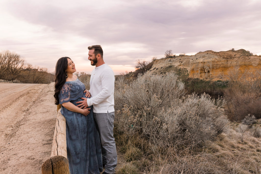 Woman in blue maternity dress and husband against desert backdrop in Boise Idaho