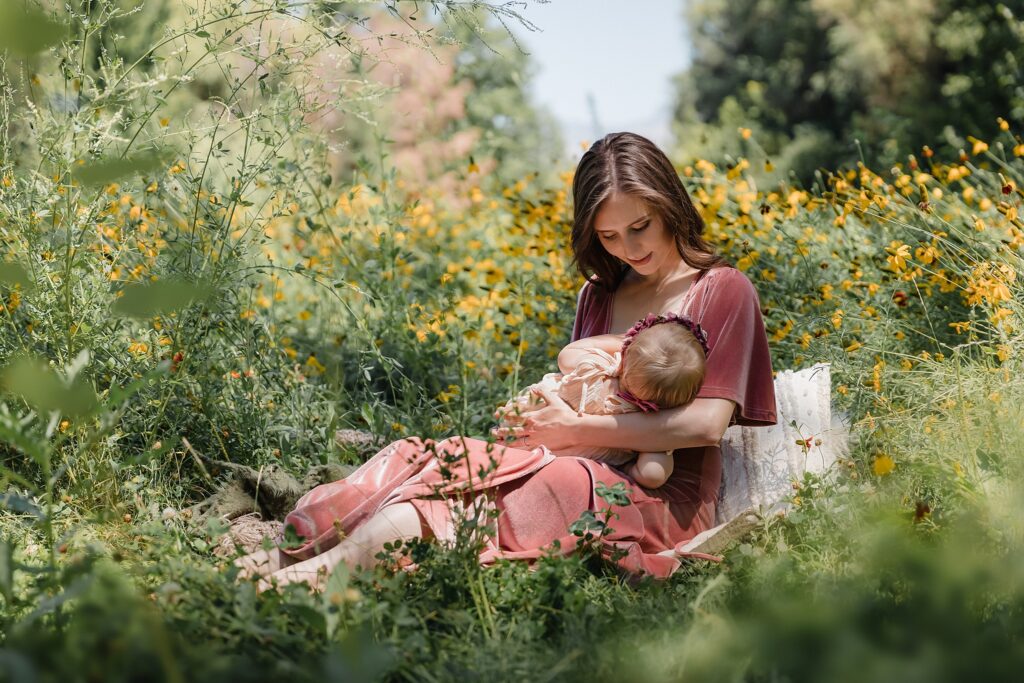 Mother rocking baby girl against backdrop of yellow flowers, best places for spring and summer family photos