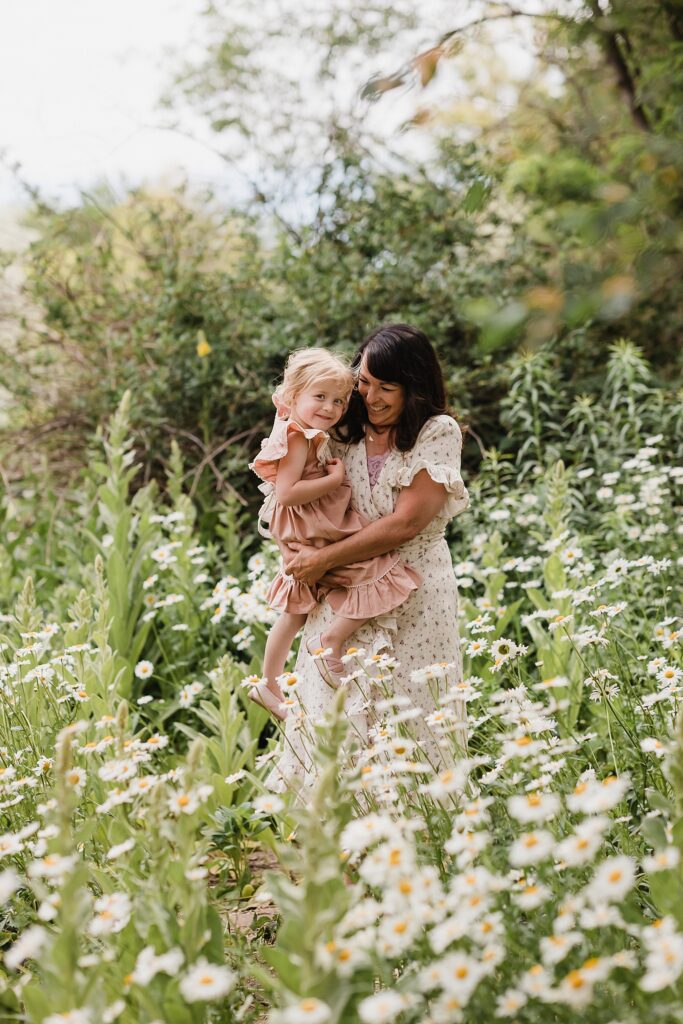 Mom and daughter smiling among daisies during outdoor photoshoot in Boise, Idaho