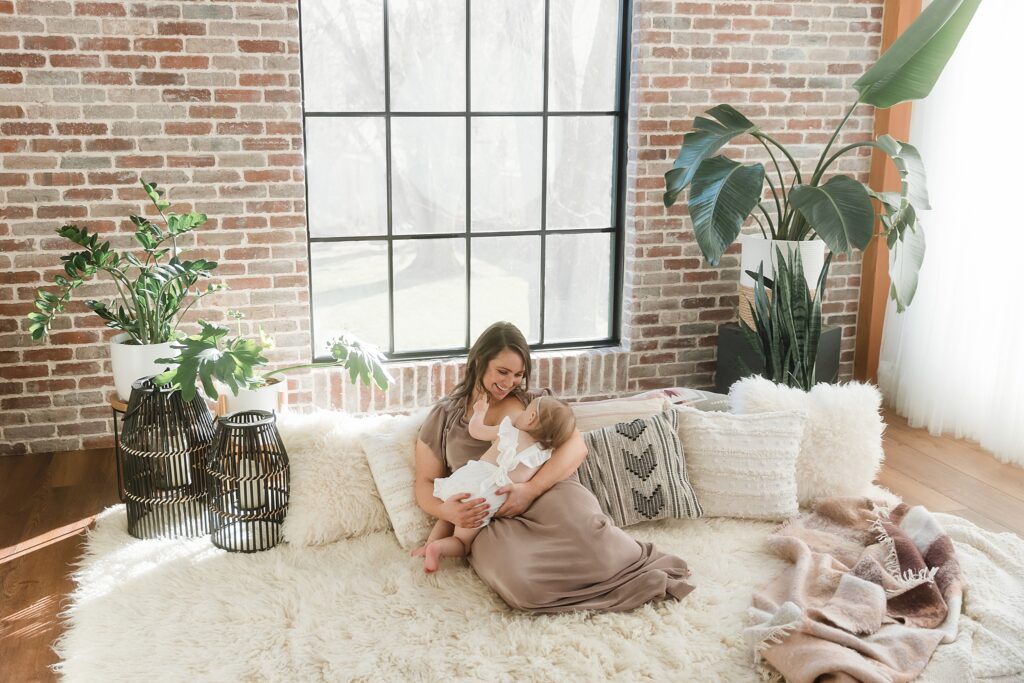 Mother and child leaning against pillows in a living room setup in studio for Boise breastfeeding portraits