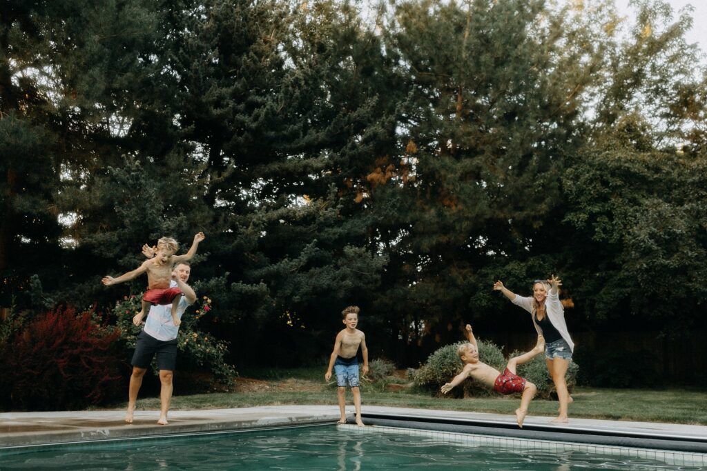 image of a boise fall family photo in the backyard with kids being tossed in the pool for a relaxed choice of location