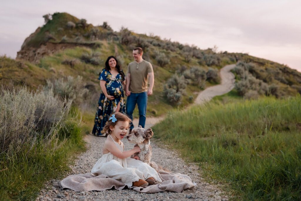 Boise foothills maternity photo with toddler and dog in foreground, parents walking behind