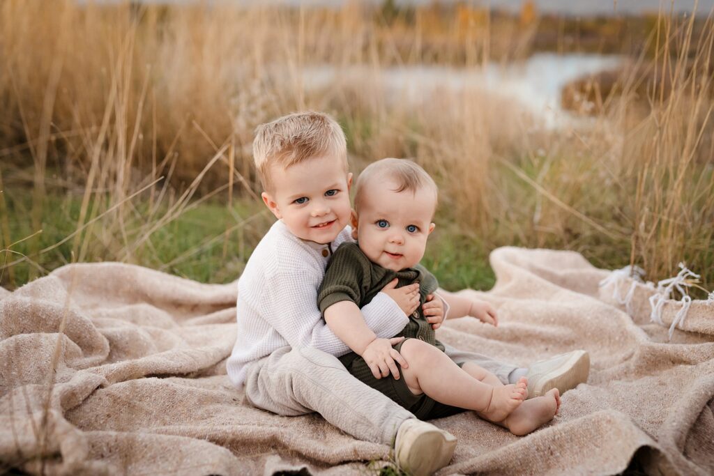 Two young boys sitting on neutral blanket during fall photo session in Boise Idaho