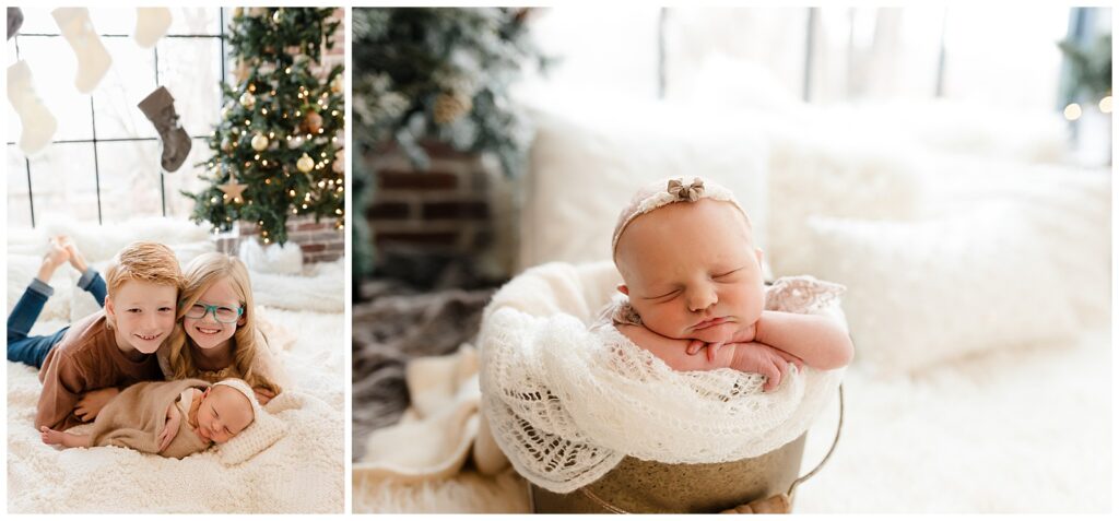 newborn baby girl dressed in neutral holiday decor with christmas trees in the background and her two older siblings smiling above her