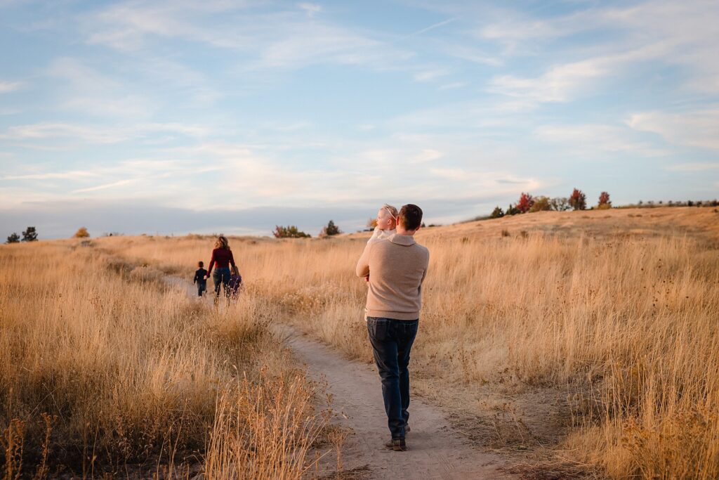 a dad walking with his young daughter in his arms in the foothills of boise idaho by professional family photography studio, Glean and Co