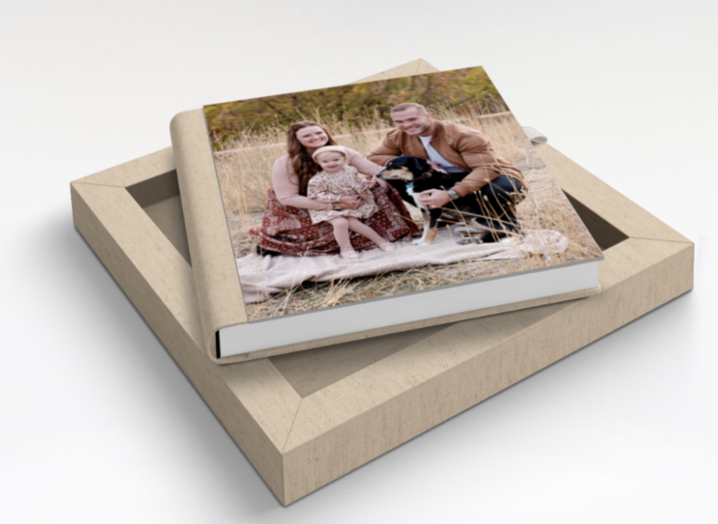 a family photo album, displayed in a linen box with a photo on the cover of the album with a little girl, mom and dad and their dog. 