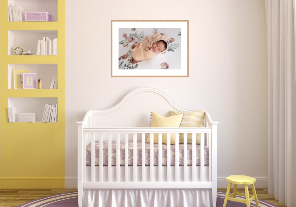 Newborn baby girl sleeps peacefully in a soft yellow bonnet while swaddled in white, her nursery's matching yellow accents visible in the background creating a harmonious color story between baby and space