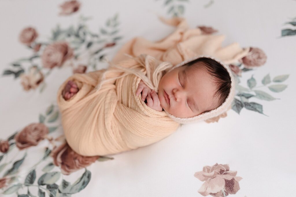 Newborn photography session thoughtfully styled to complement baby girl's nursery - her delicate yellow bonnet echoes the sunshine tones of her carefully designed room, creating cohesive portraits that will be displayed in her space