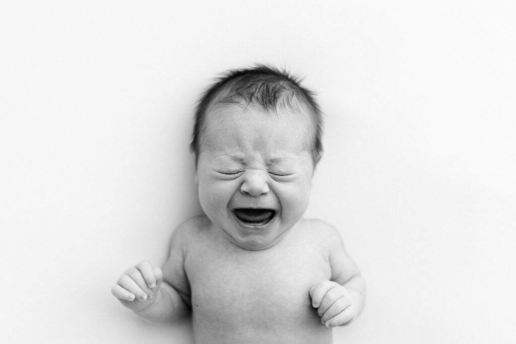 a retouched black and white image of a newborn baby crying
