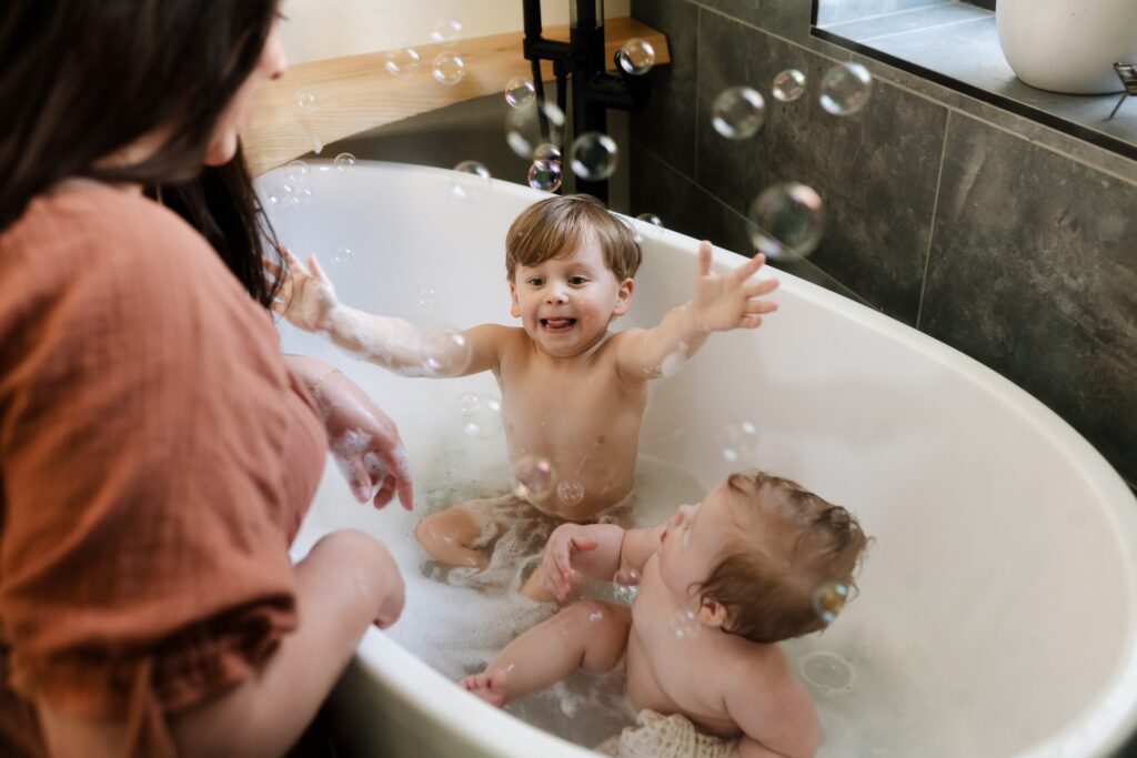 Siblings sharing bath time after their cake smash adventure, both clean and happy after the messy fun