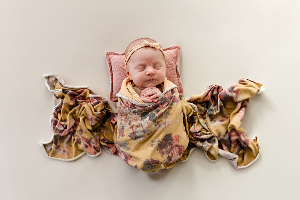 wrapped newborn portrait of a baby girl on a cream background. shots like this are easy during quick mini newborn sessions