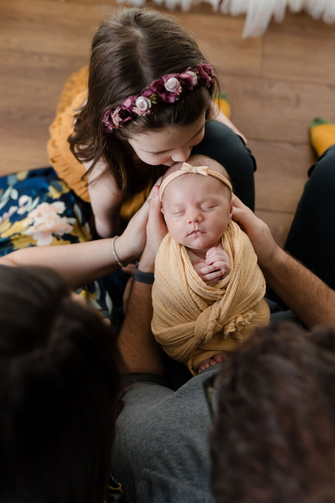 big sister kisses her new baby sister during a lifestyle mini newborn session with Glean and Co Photography in Boise Idaho