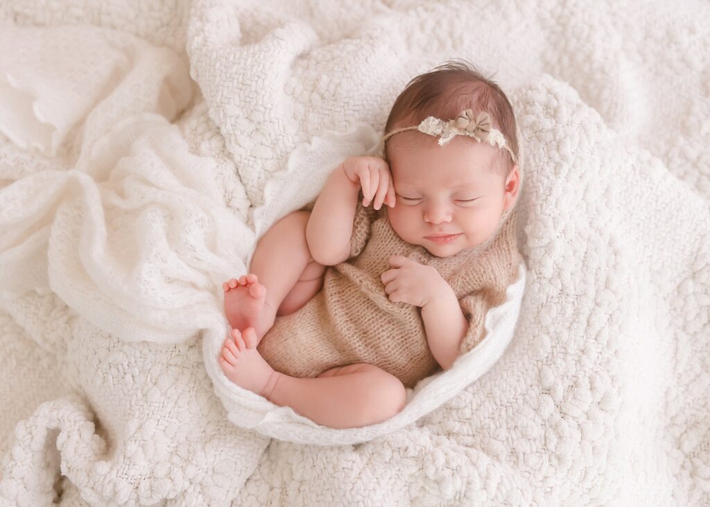 Newborn baby girl sleeping on white blanket with soft natural lighting in photography studio