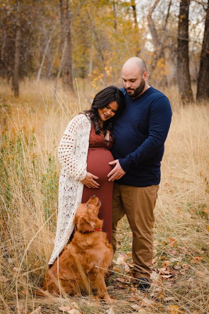 Happy couple laughing with dog during twin maternity session shot along the Boise Greenbelt