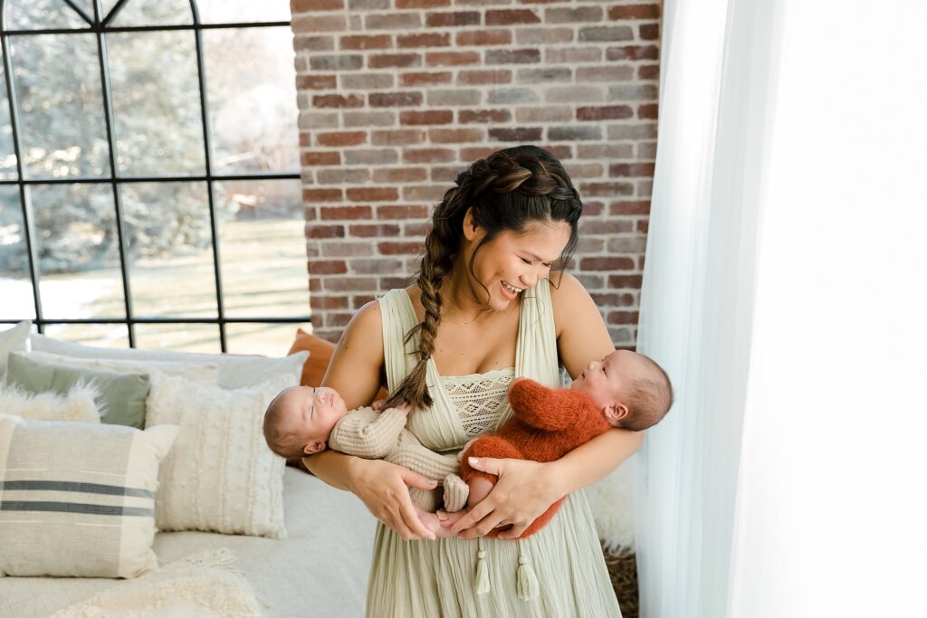 Mother holding twin newborn babies in Glean and Co photography studio in Boise