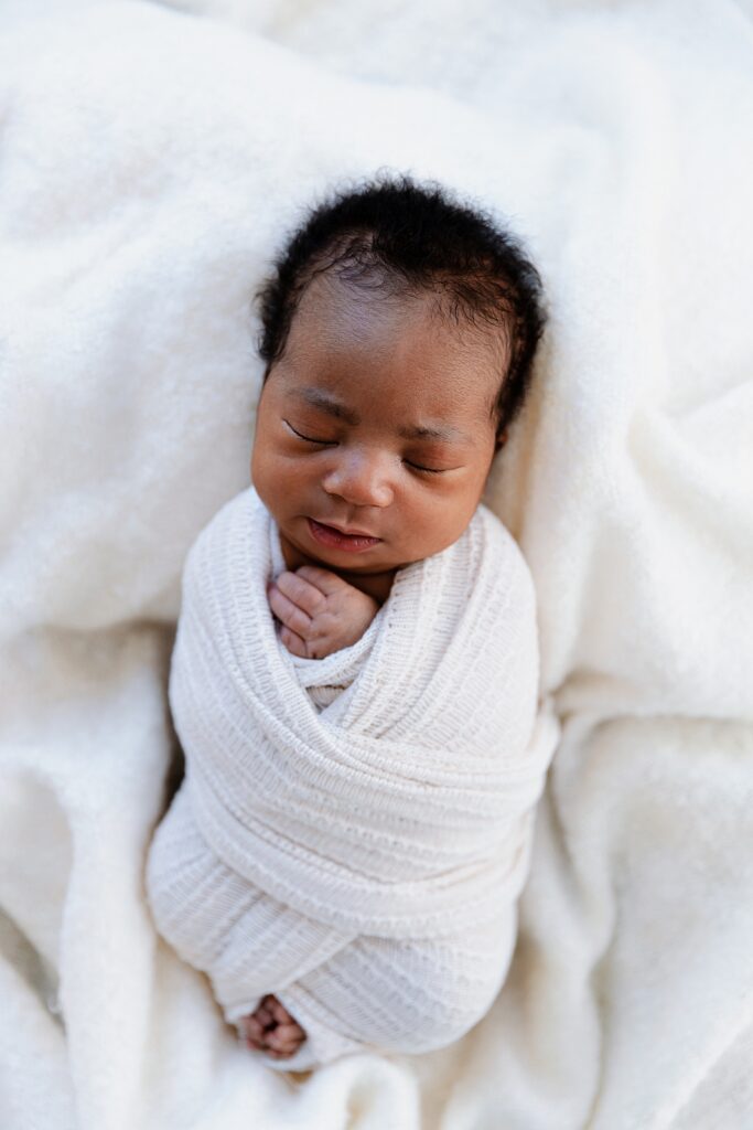 Newborn baby boy with natural skin tones lying on white background after fixing orange skin tones with photoshop color correction techniques