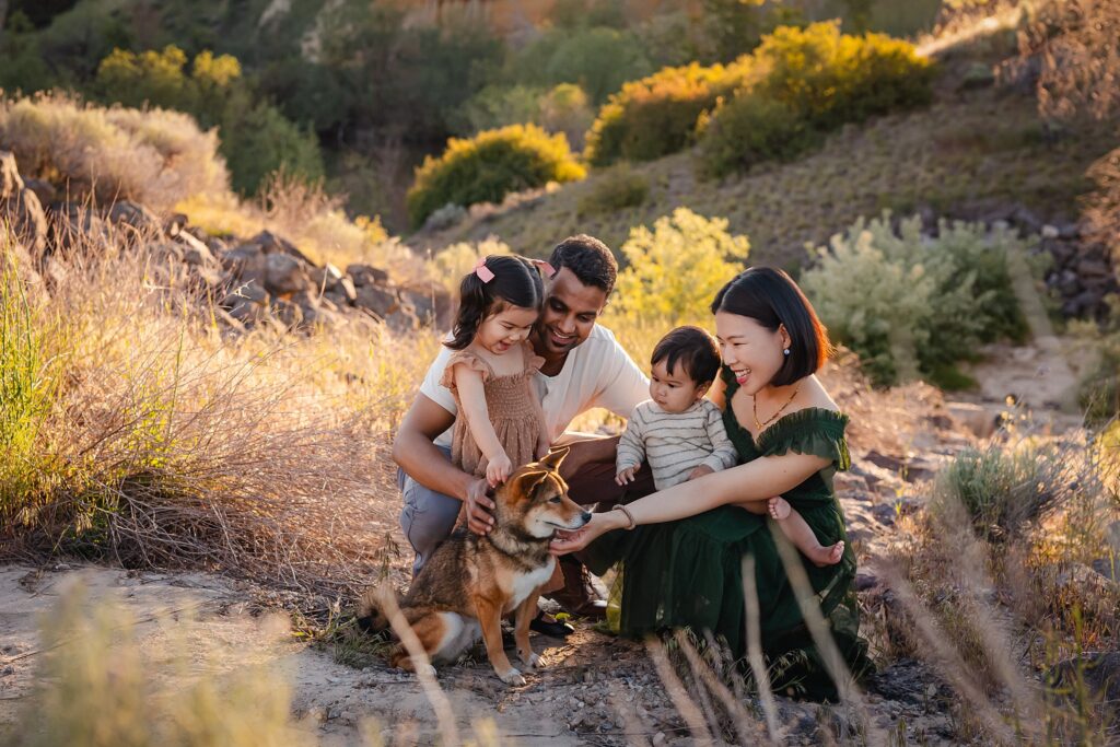 Family photography with dogs session featuring parents and children petting their dog during golden hour shoot in Boise foothills location