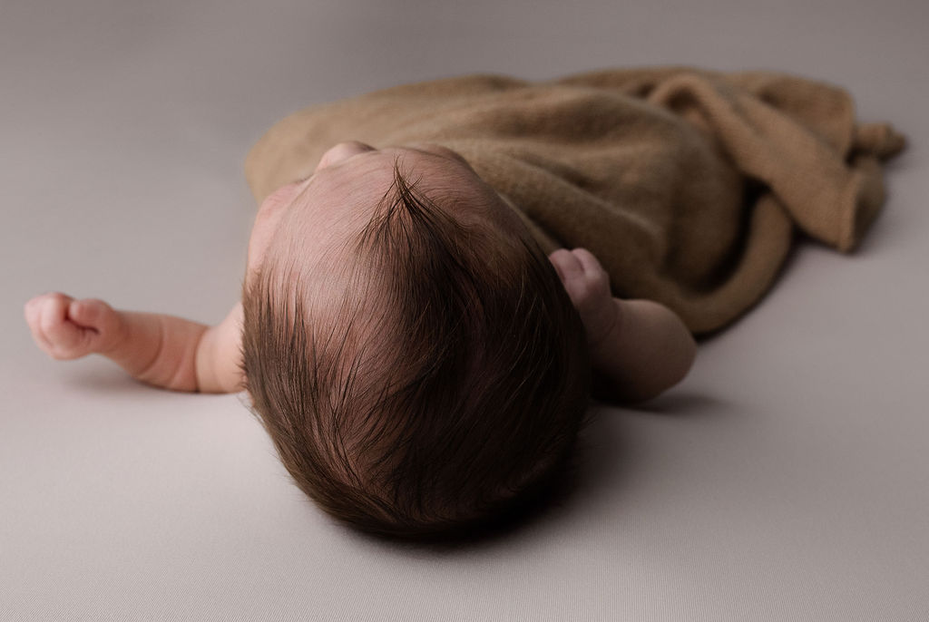 Overhead view of sleeping newborn's hair and tiny hand detail shot