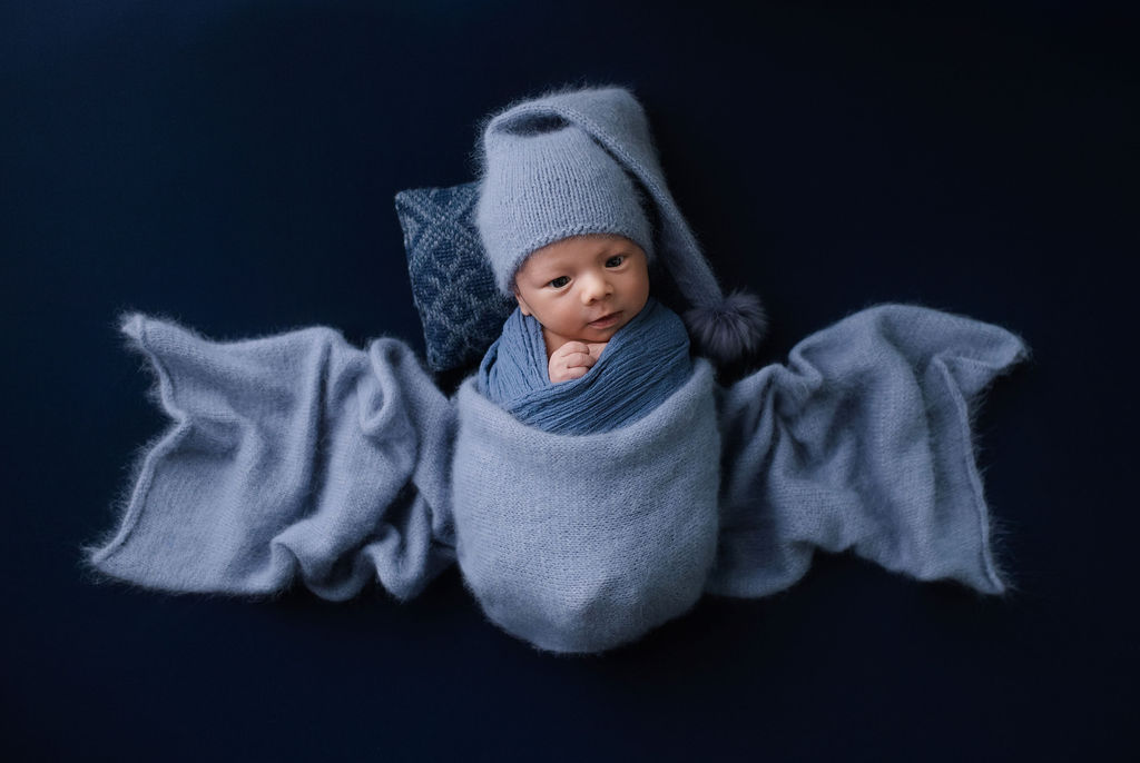 Newborn baby in blue knit hat nestled in soft blankets during studio session with Glean and Co in Boise Idaho