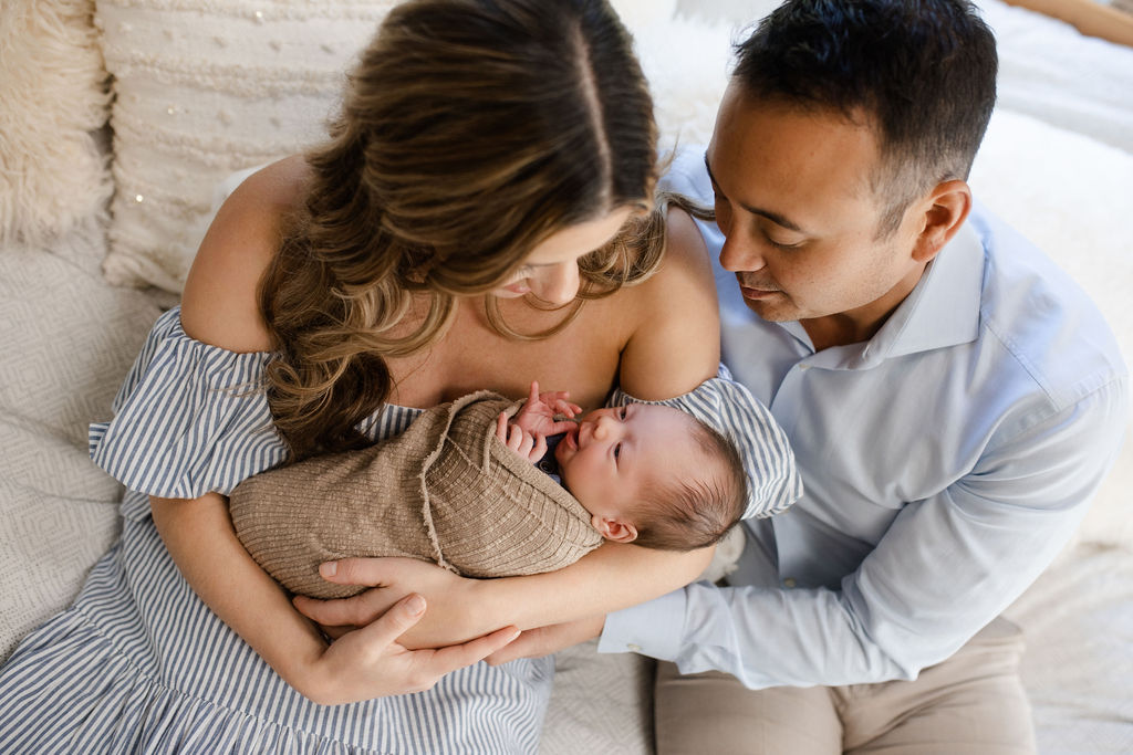 Parents lovingly holding their newborn baby during relaxed family photography session in Boise Idaho