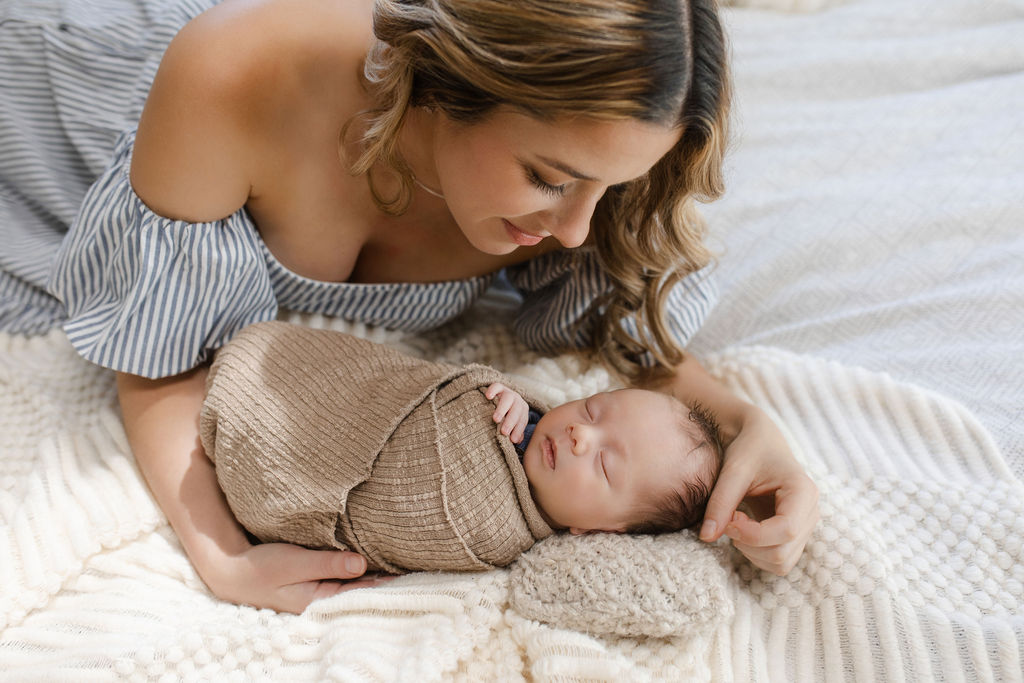 Mother gently stroking her newborn baby's soft hair during relaxed newborn photography session in Glean and Co lifestyle studio