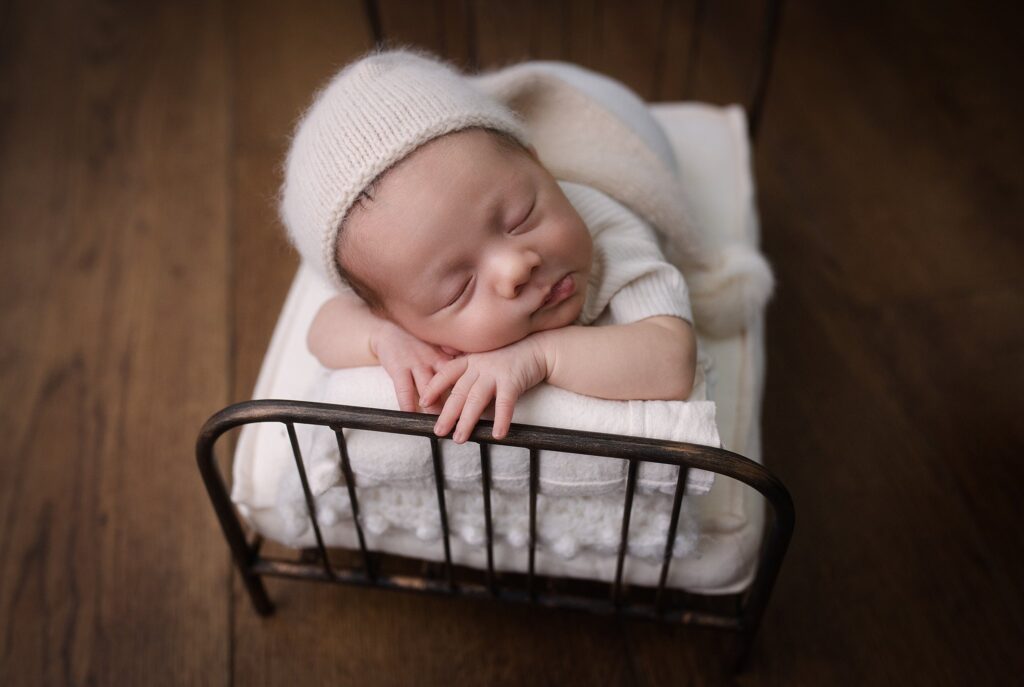 Newborn baby boy peacefully sleeping on soft bed photographed by the best newborn photographer in Boise