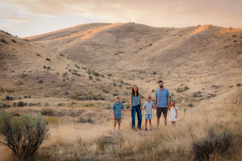 Sweeping foothills behind a family of 5 at sunset during a family photography session at Harrison Hollow trail in Boise, Idaho
