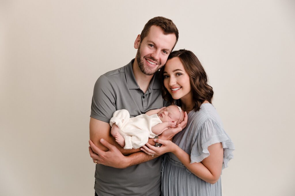 Parents cradling their newborn baby during a posed studio newborn photography session with soft professional lighting in SE Boise