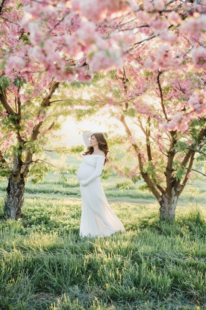 spring maternity session in Boise with pink cherry blossoms and beautiful mom to be in a white dress by Glean and Co Photography and Idaho's best pregnancy photographer