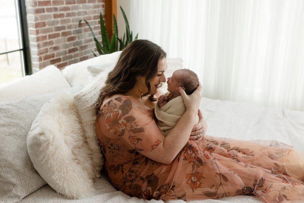 Mother smiling at alert newborn baby during natural light lifestyle newborn session at Glean and Co Photography studio Boise Idaho