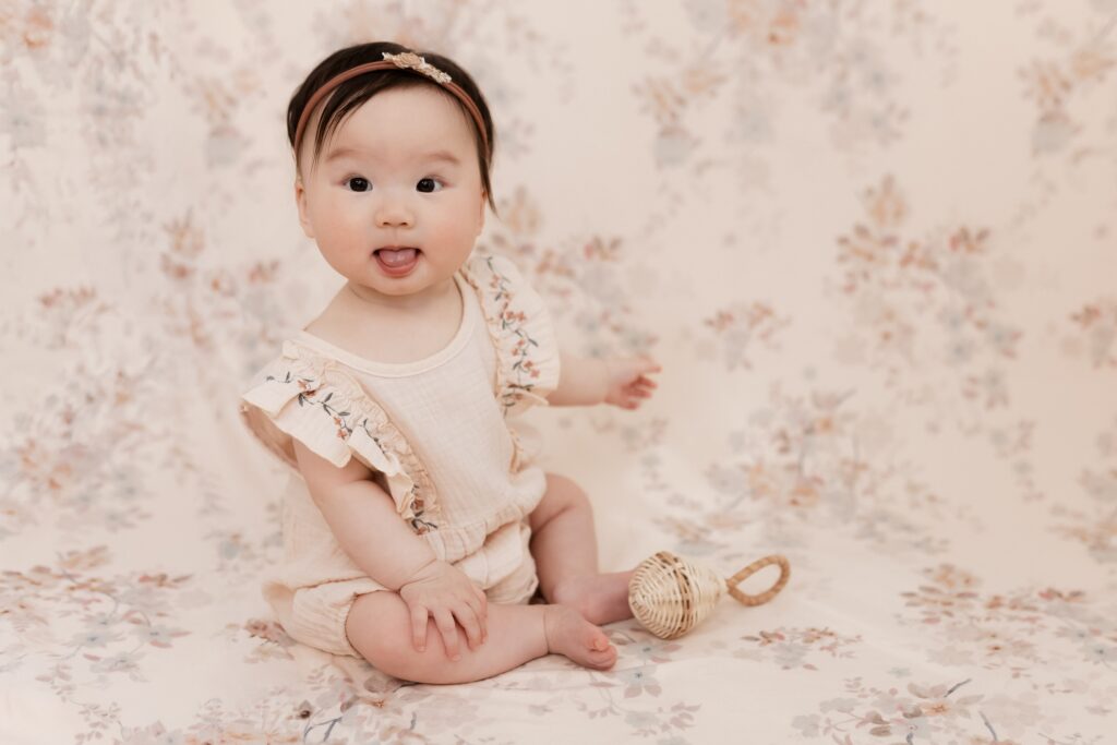 Milestone photos of baby girl on floral background from Hello Little Props with simple neutral rattle